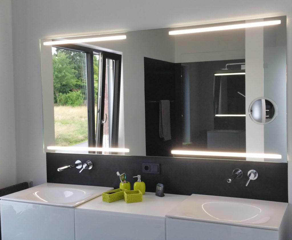 Badezimmer mit hinterleuchtetem Spiegel.